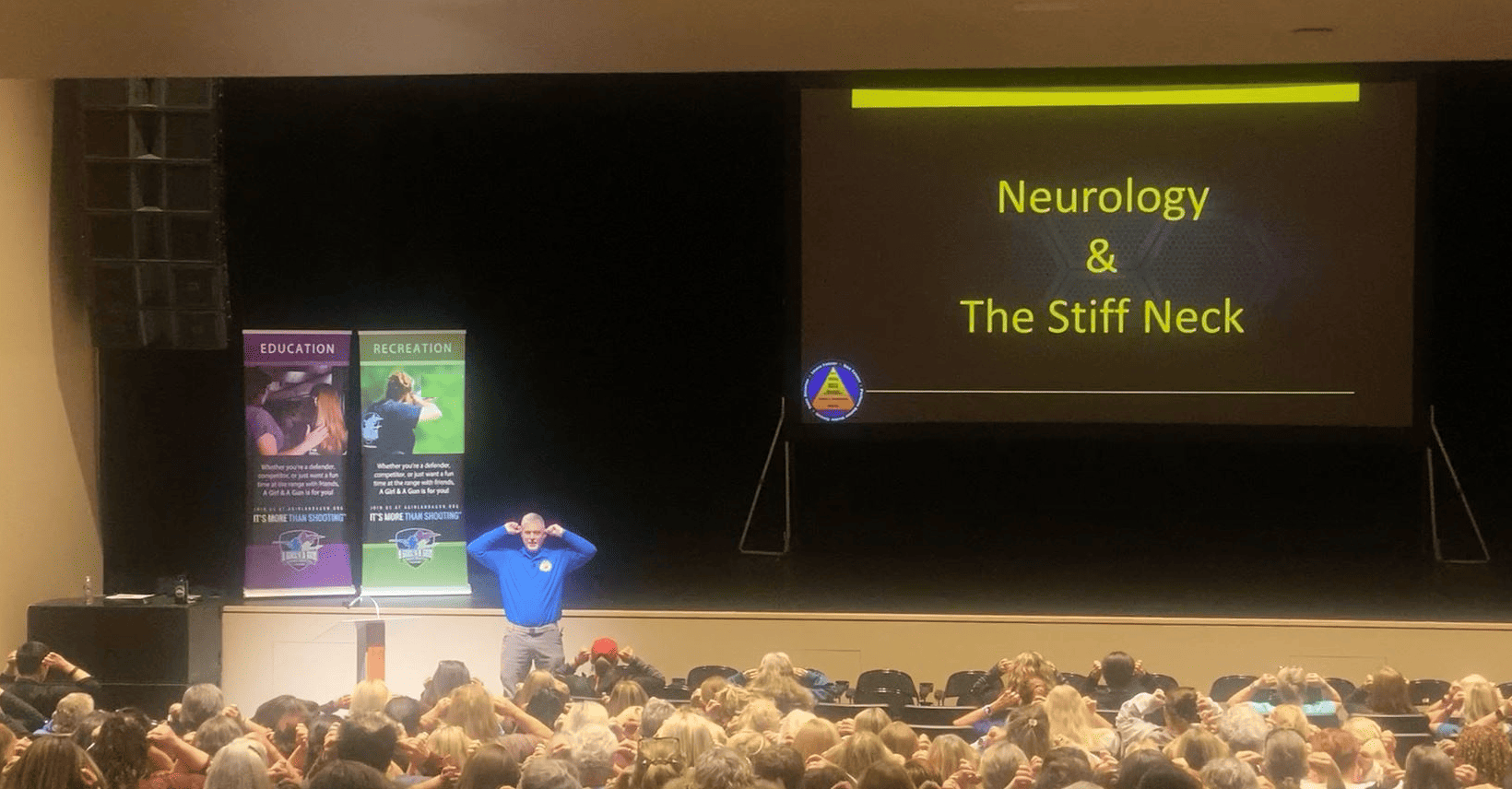 Mike leading a full auditorium through the Ear Pulls drill